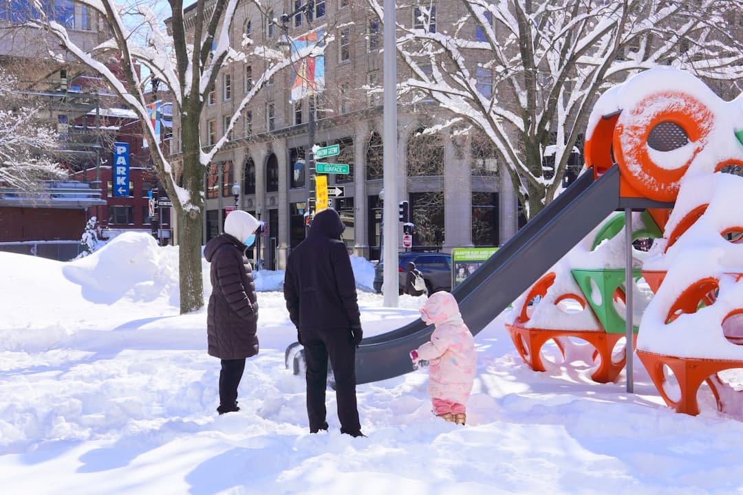 Family in snowy park with colorful playground equipment. — Photo by Brett Wharton on Unsplash