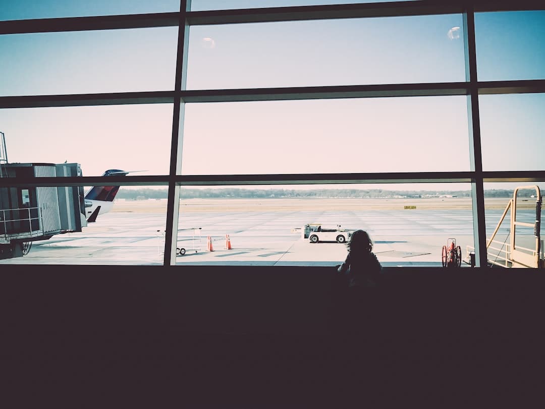a person looking out a window at an airport — Photo by Kelly Sikkema on Unsplash